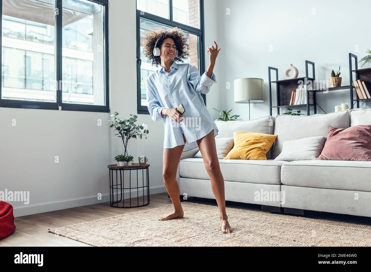 Felice giovane donna che indossa cuffie da ballo a casa Foto Stock
