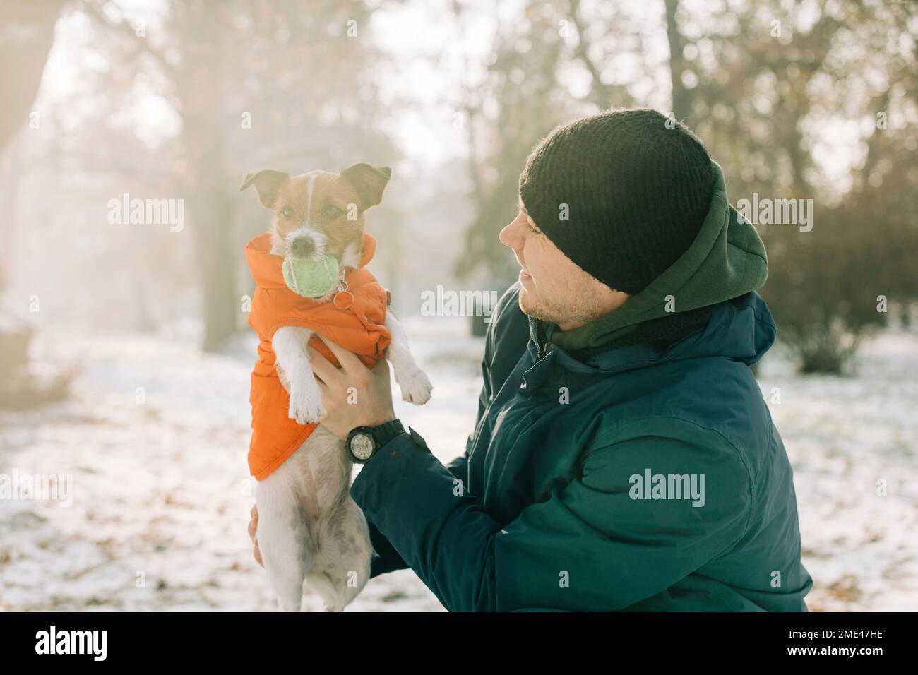Uomo sorridente che gioca con il cane da compagnia in inverno Foto Stock