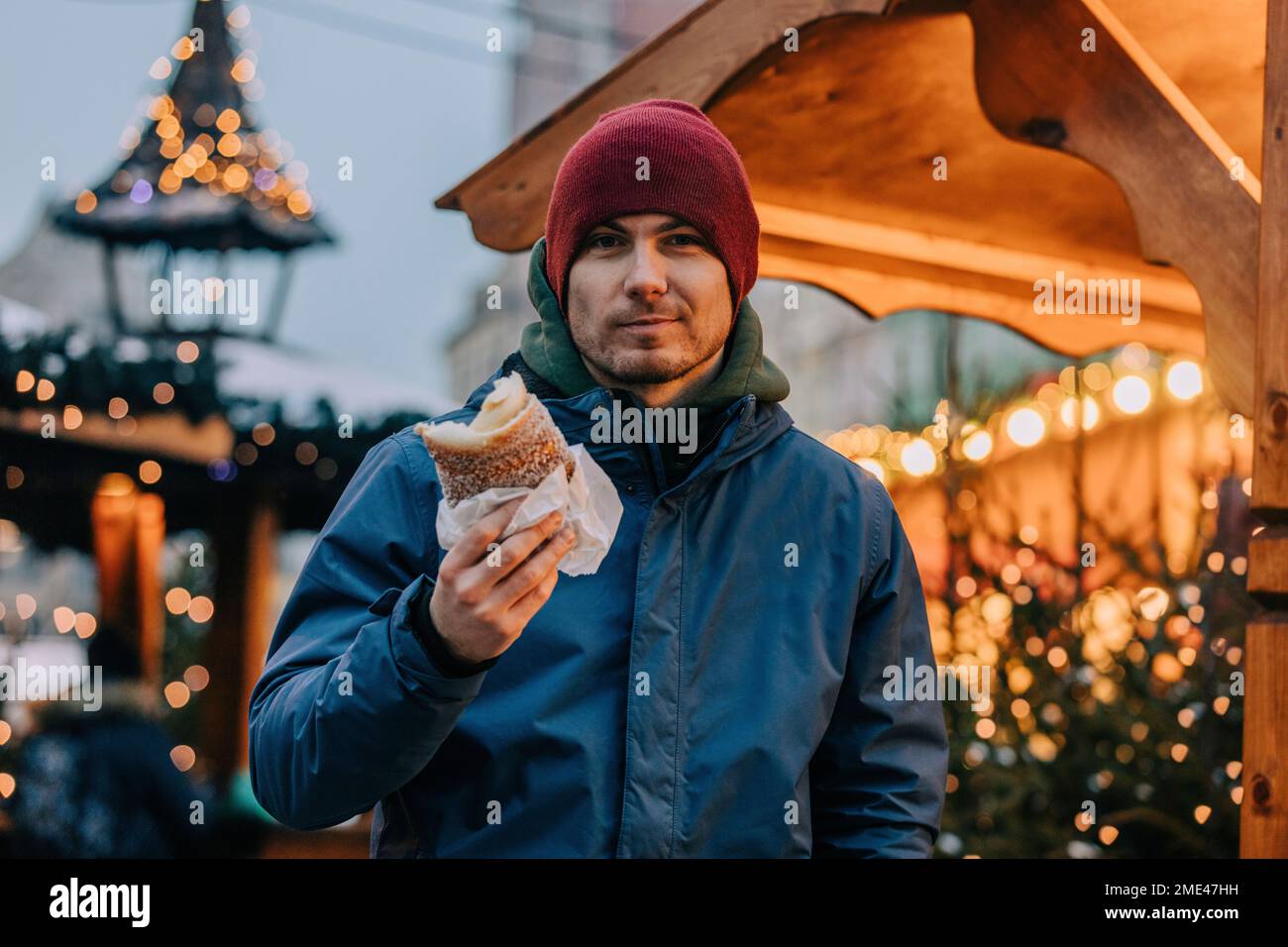 Uomo sorridente che tiene trdelnik alla fiera di Natale Foto Stock
