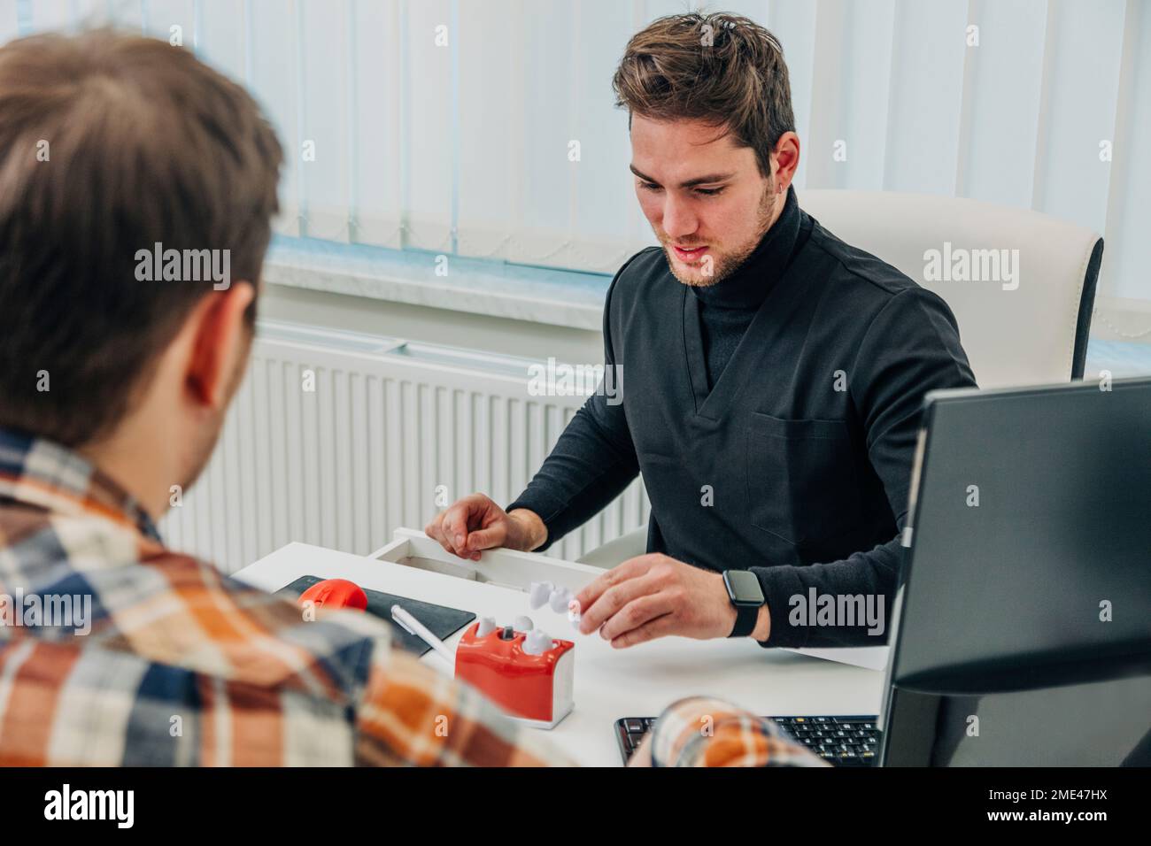 Il dentista consulta il paziente su apparecchiature dentali Foto Stock