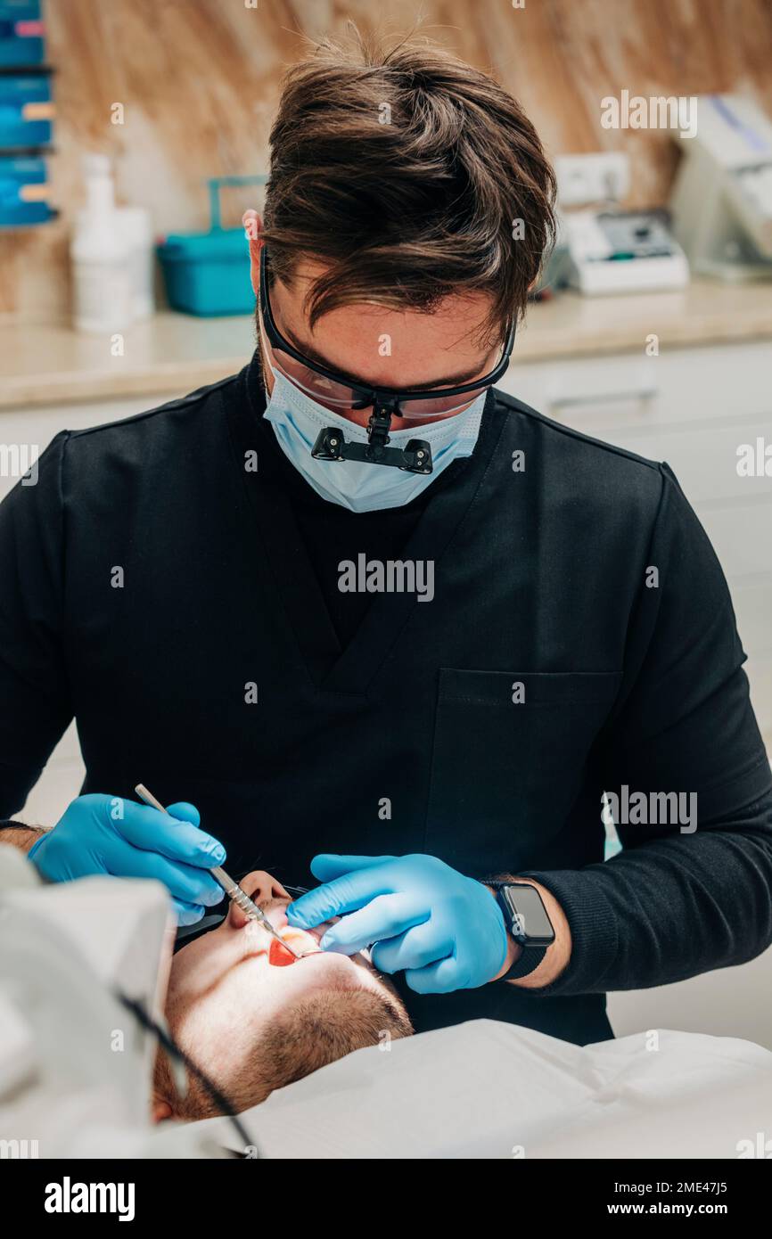 Dentista esaminando denti del paziente in clinica Foto Stock