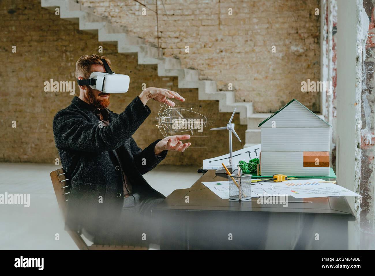 Uomo d'affari che indossa un simulatore VR gesturing con il design di turbine eoliche in cantiere Foto Stock