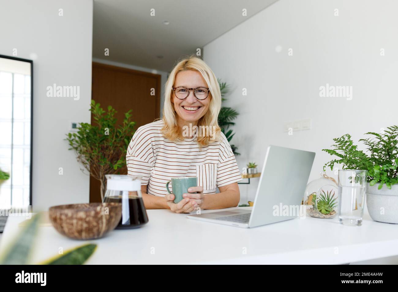 Felice freelancer indossando occhiali seduti alla scrivania Foto Stock