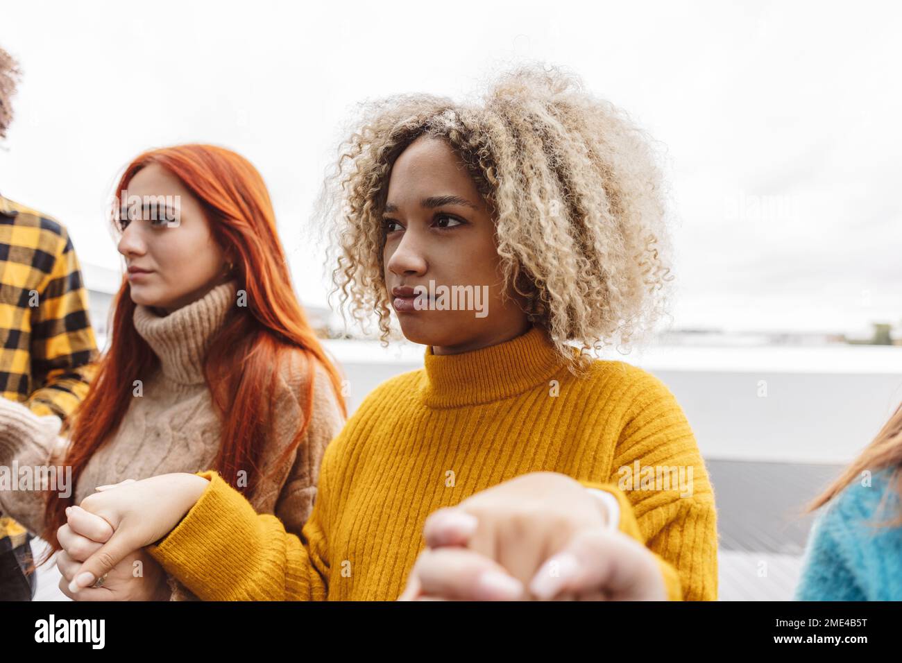 Donna con capelli ricci che tiene le mani l'una con l'altra per protesta Foto Stock