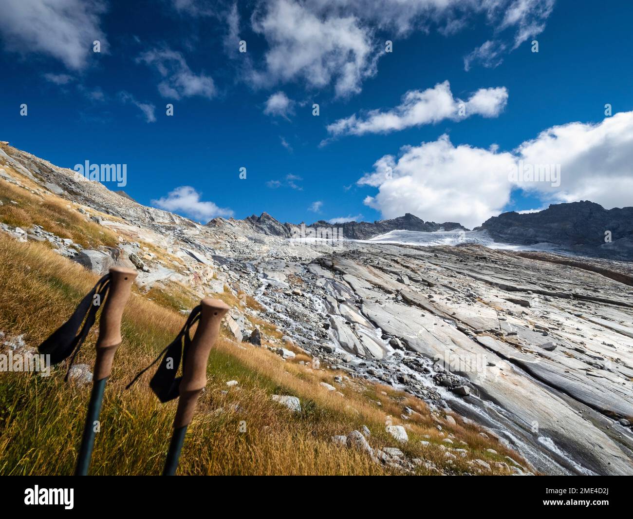 Francia, Auvergne-Rodano-Alpi, paesaggio montagnoso del Parco Nazionale della Vanoise con pali da trekking in piedi in primo piano Foto Stock