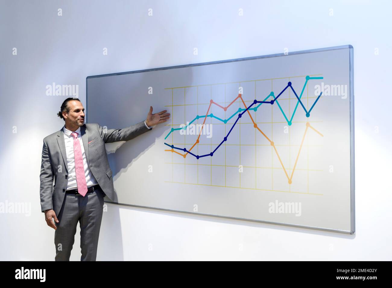 Uomo d'affari maturo che mostra il grafico sulla lavagna nella sala conferenze dell'ufficio Foto Stock