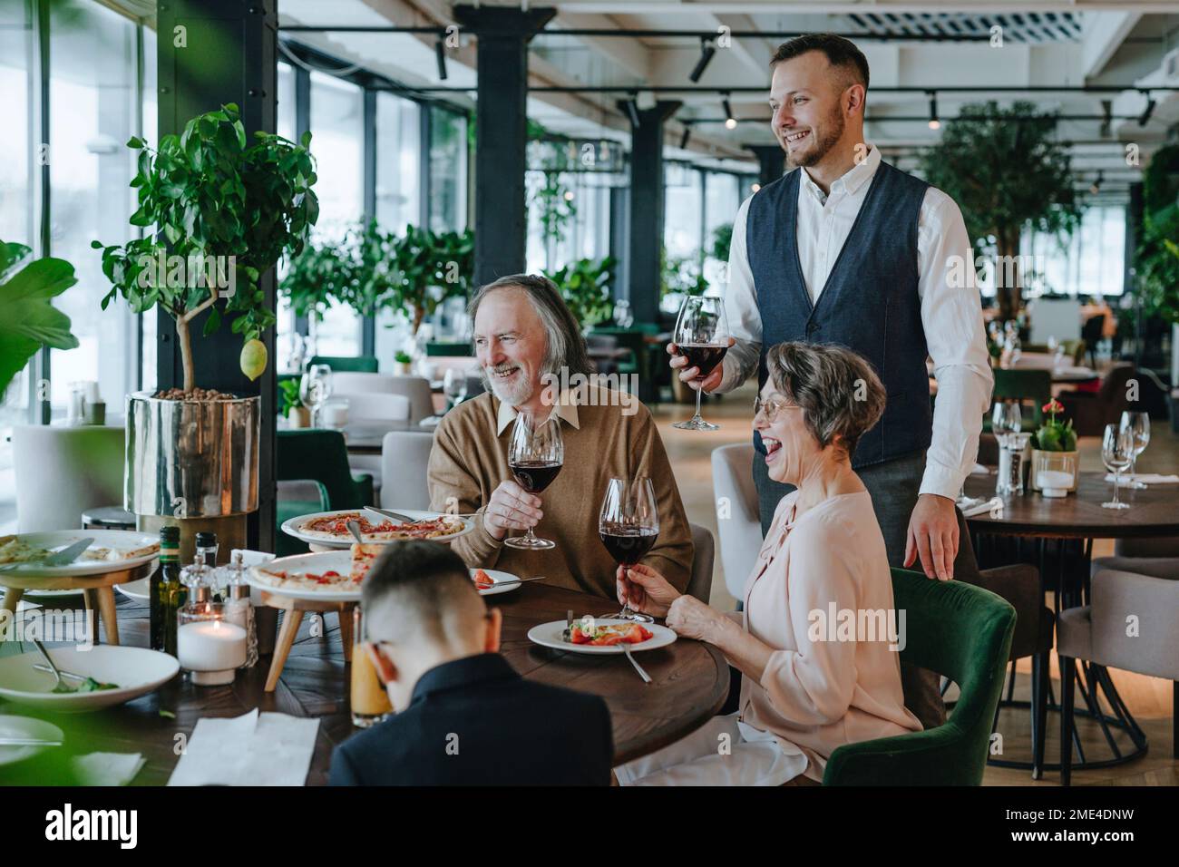 Buona famiglia gustando il cibo seduto al tavolo da pranzo nel caffè Foto Stock