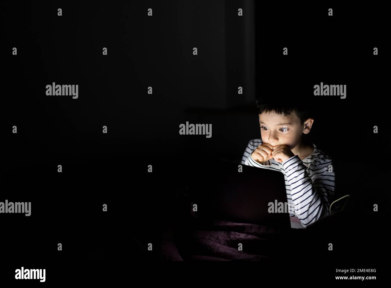 Ragazzo che guarda film spaventosi sul notebook a casa Foto Stock