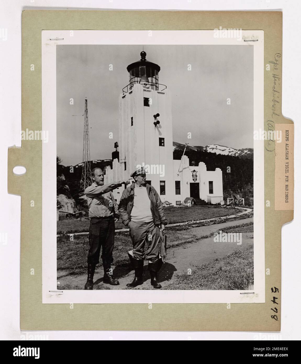 Mantiene la veglia dell'Alaska per i marinai (2 di 7). A sinistra in questa fotografia è Arie Van Der Meet, Jr., compagno di boatswain seconda classe, di Seattle, Washington, che è responsabile degli Stati Uniti Stazione della Guardia Costiera leggera a Cape Hinchinbrook, Alaska. Dopo un giro di un anno di servizio come guardiano della luce, sarà ruotato di nuovo negli Stati Uniti. Qui sta indicando le attrazioni alla stazione al comandante James S. Muzzy, anche di Seattle, ufficiale esecutivo del NORTHWIND, durante la visita di rifornimento della nave a Hinchinbrook. Dietro di loro si trova la stazione, situata sul lato est dell'entrata di Hinchinbrook al Principe Foto Stock