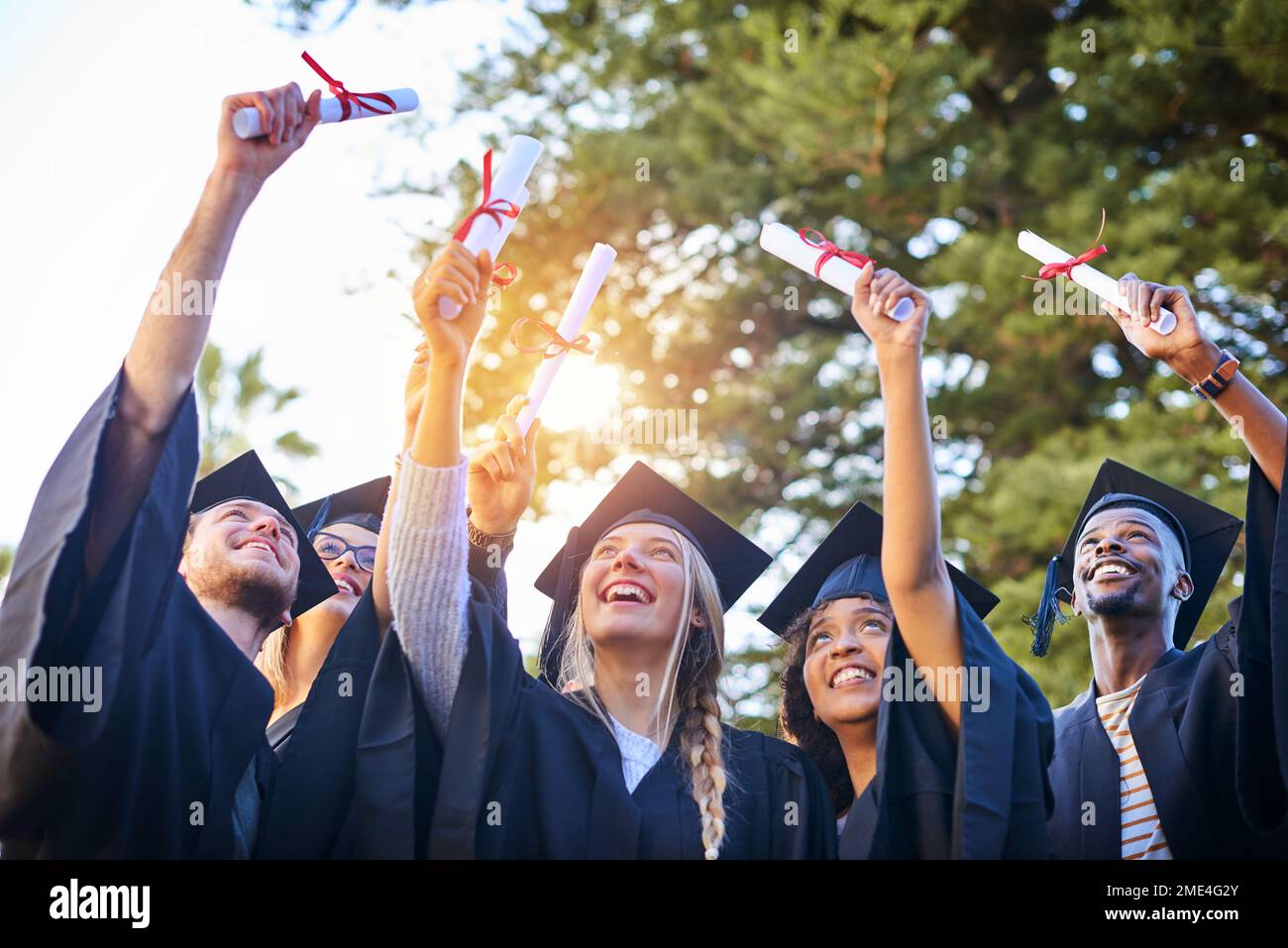 Prendetevi un momento per assaporare la realizzazione della laurea. un gruppo di laureati in possesso dei loro diplomi in aria. Foto Stock