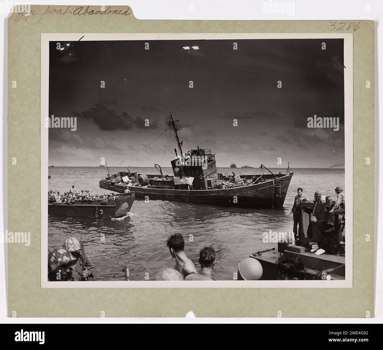 Le imbarcazioni da sbarco con equipaggio della Guardia Costiera passano davanti a una barca giapponese abbandonata mentre si avvicinano all'isola Carlos, l'atollo di Kwajalein, durante il bombardamento pre-assalto dell'attacco di Kwajalein. Foto Stock