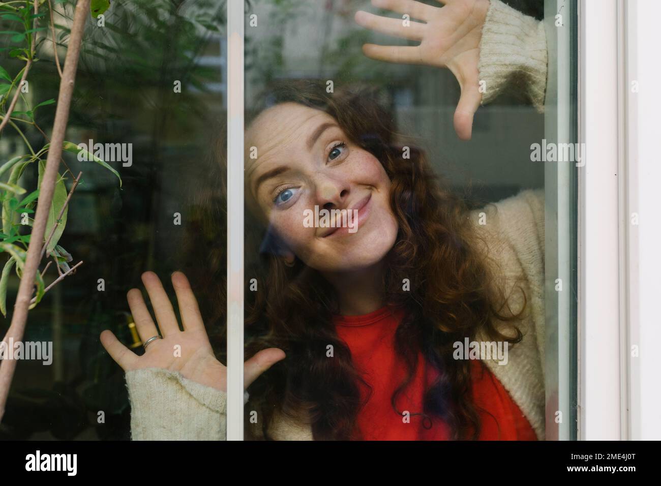 Donna sorridente che fa i volti visto vetro completo Foto Stock