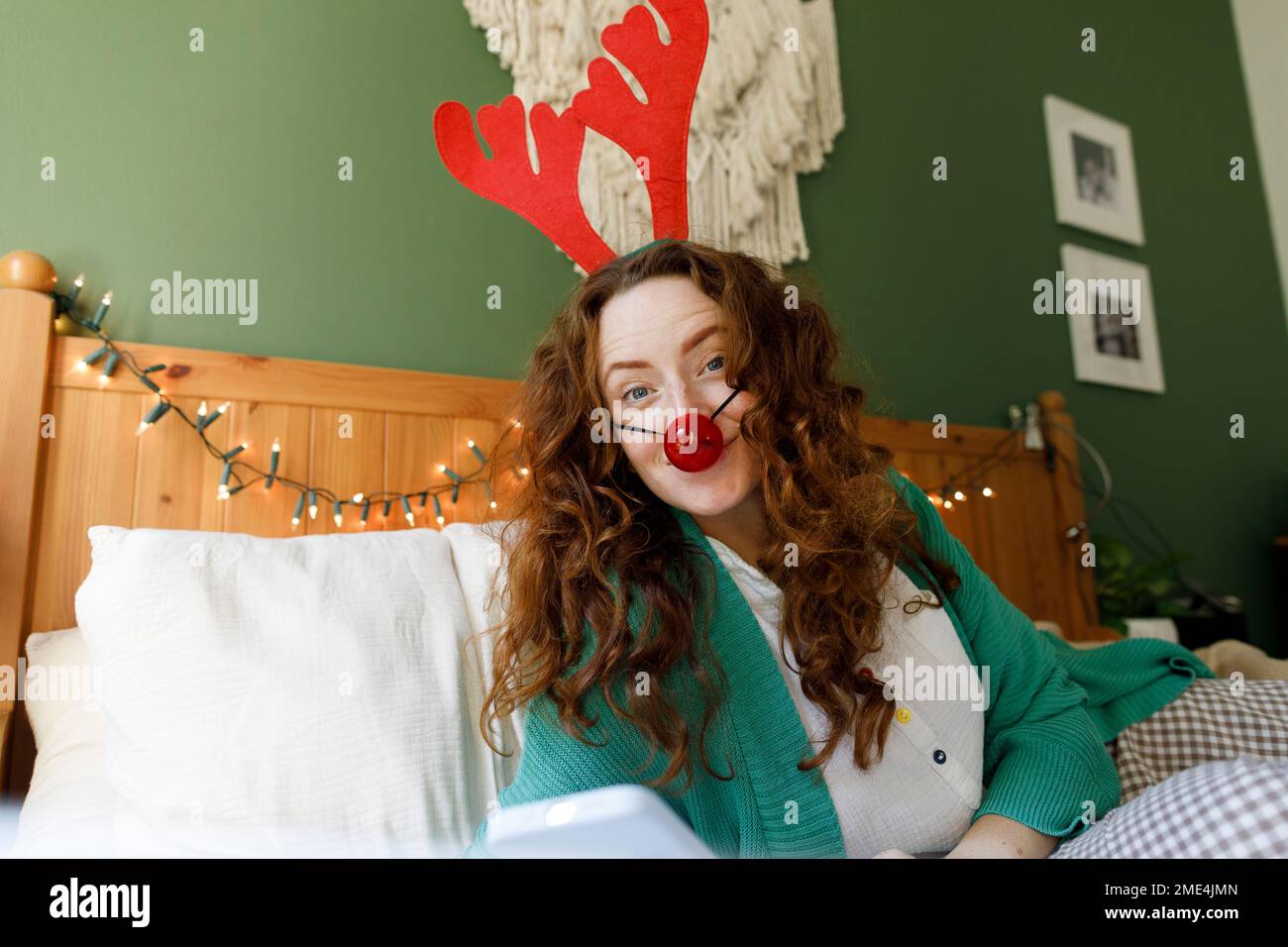 Donna che indossa corna e naso di clown in camera da letto Foto Stock