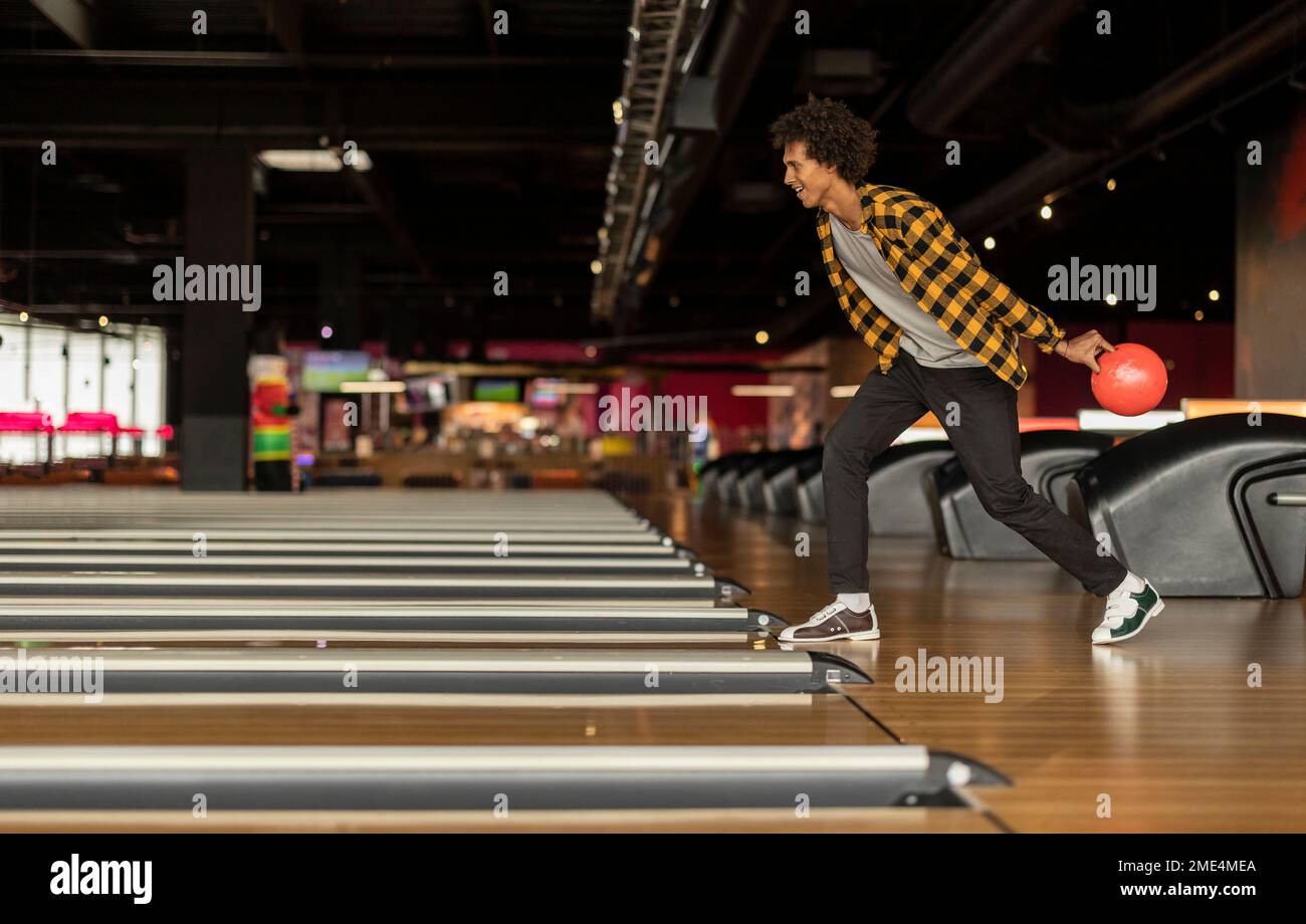 Giovane uomo che lancia la palla al bowling Foto Stock