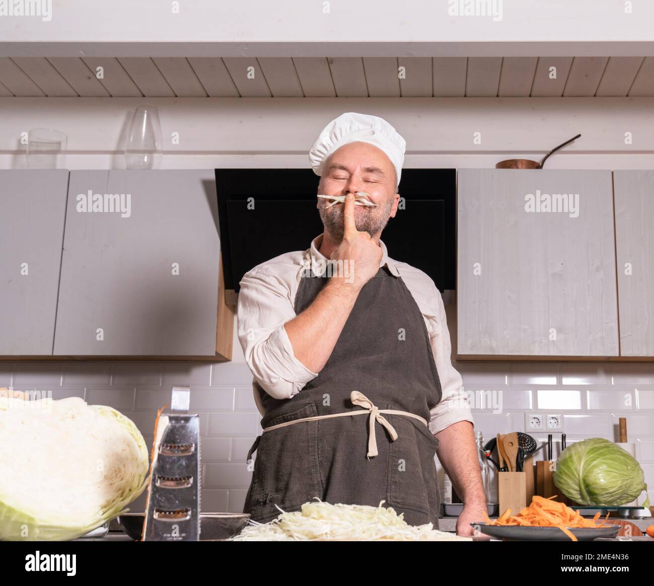 Uomo giocoso che indossa abiti da chef in cucina a casa Foto Stock