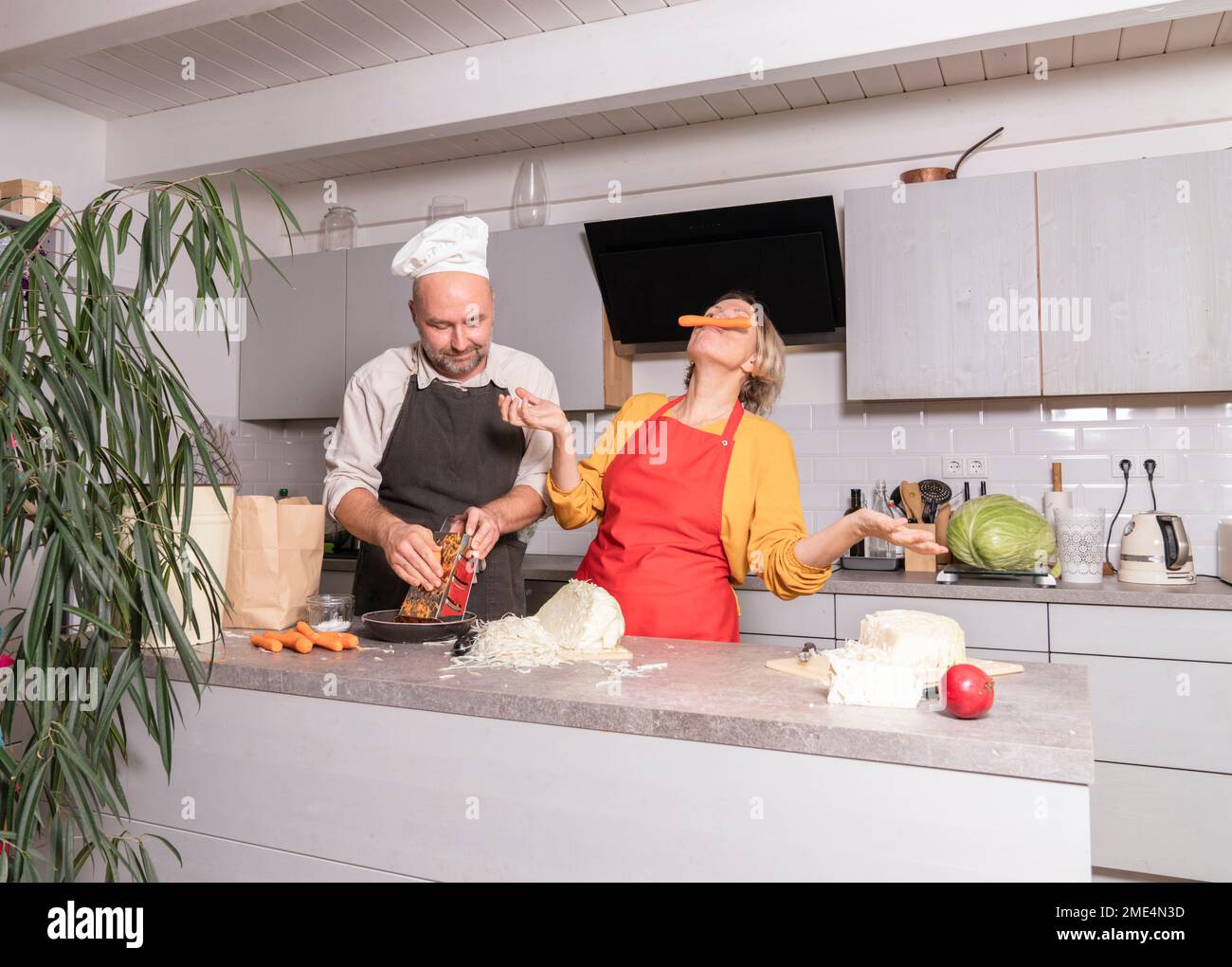 Donna di colore che indossa un grembiule in cucina e segue un video di  cucina online