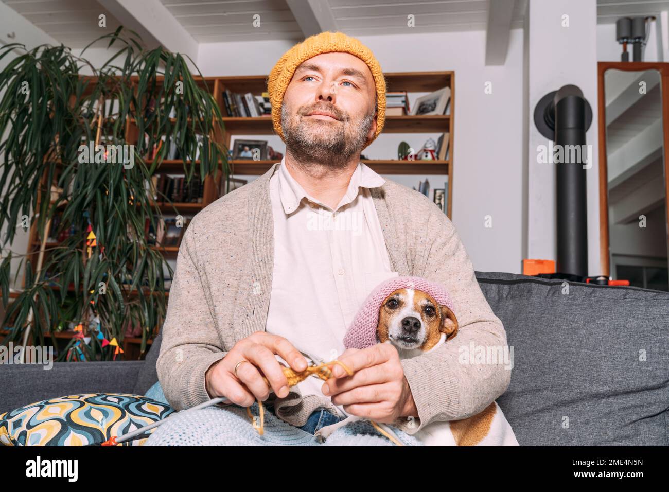 Uomo con cucito di cane sul divano a casa Foto Stock