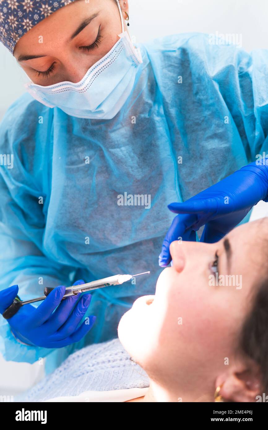 Il dentista che somministra un'iniezione anestetica al paziente in clinica Foto Stock