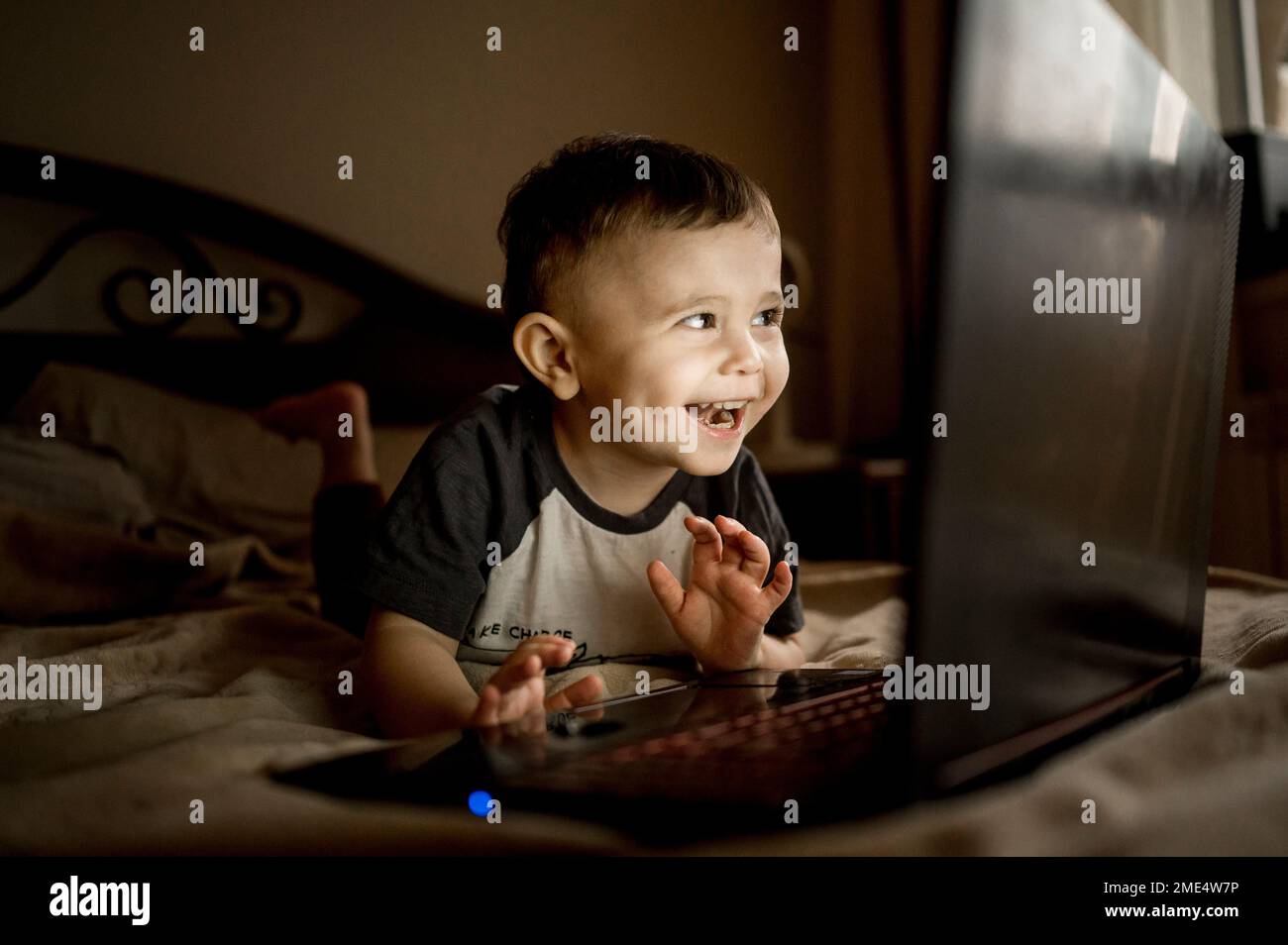 Felice ragazzo con il computer portatile sdraiato sul letto a casa Foto Stock