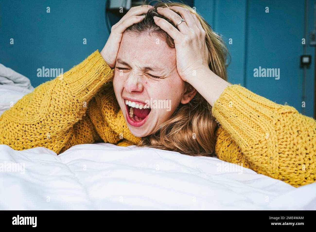 Donna stressata urlando sul letto a casa Foto Stock