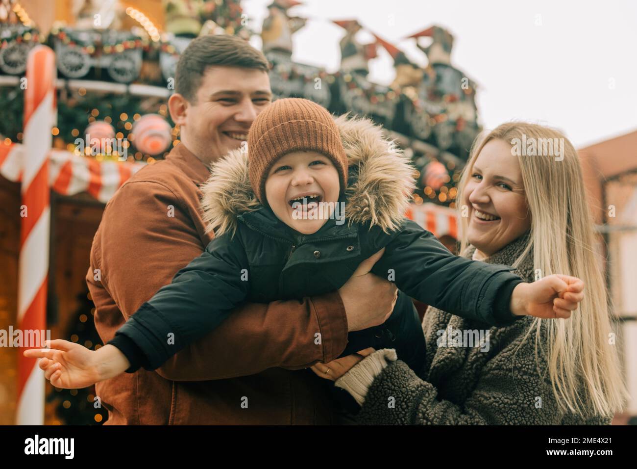 Felice padre e madre che si divertono con il figlio al mercato di Natale Foto Stock