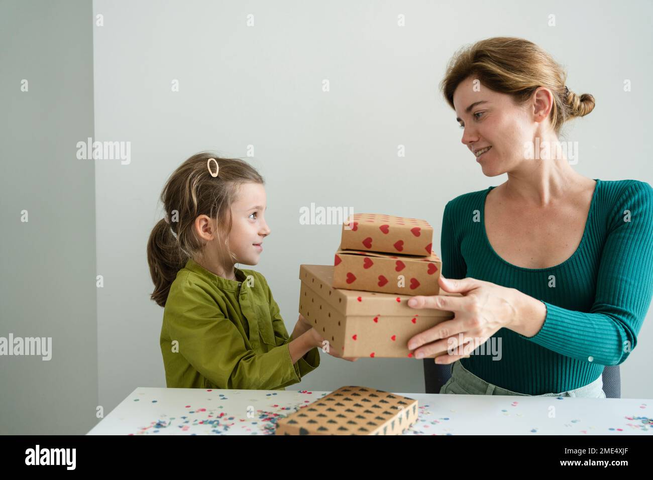 Madre che dà una pila di doni a figlia a casa Foto Stock