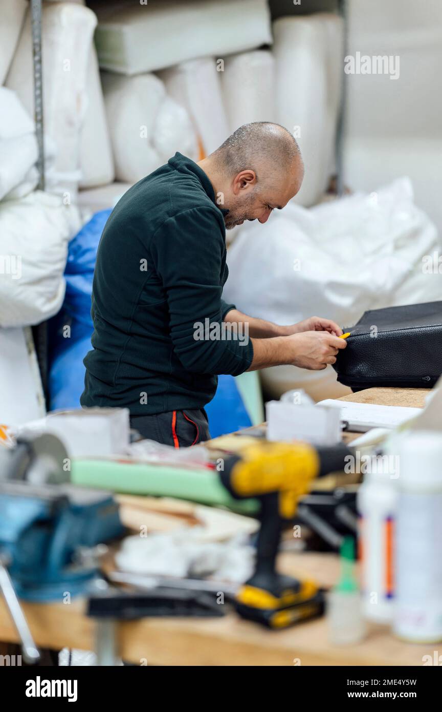 Artigiano che ripara in officina di tappezzeria Foto Stock