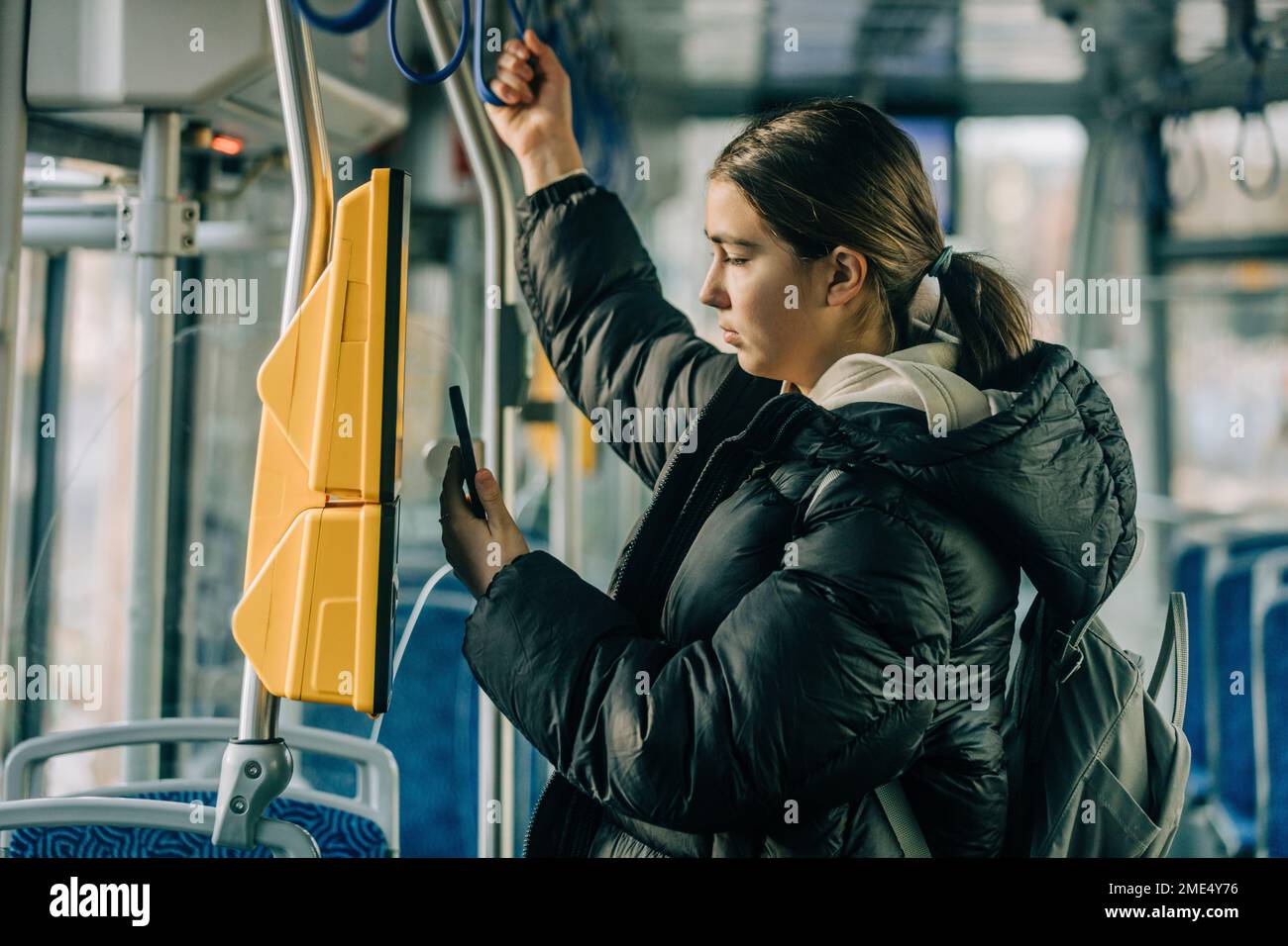 Ragazza adolescente che acquista il biglietto tramite smartphone in tram Foto Stock