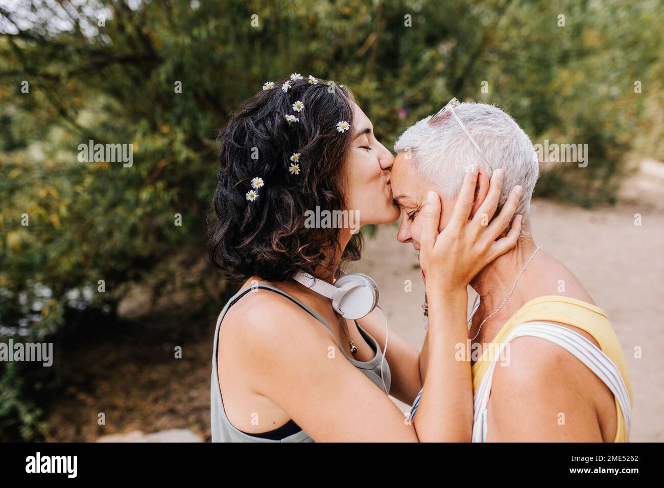 Giovane donna che bacia amico sulla fronte al parco Foto Stock