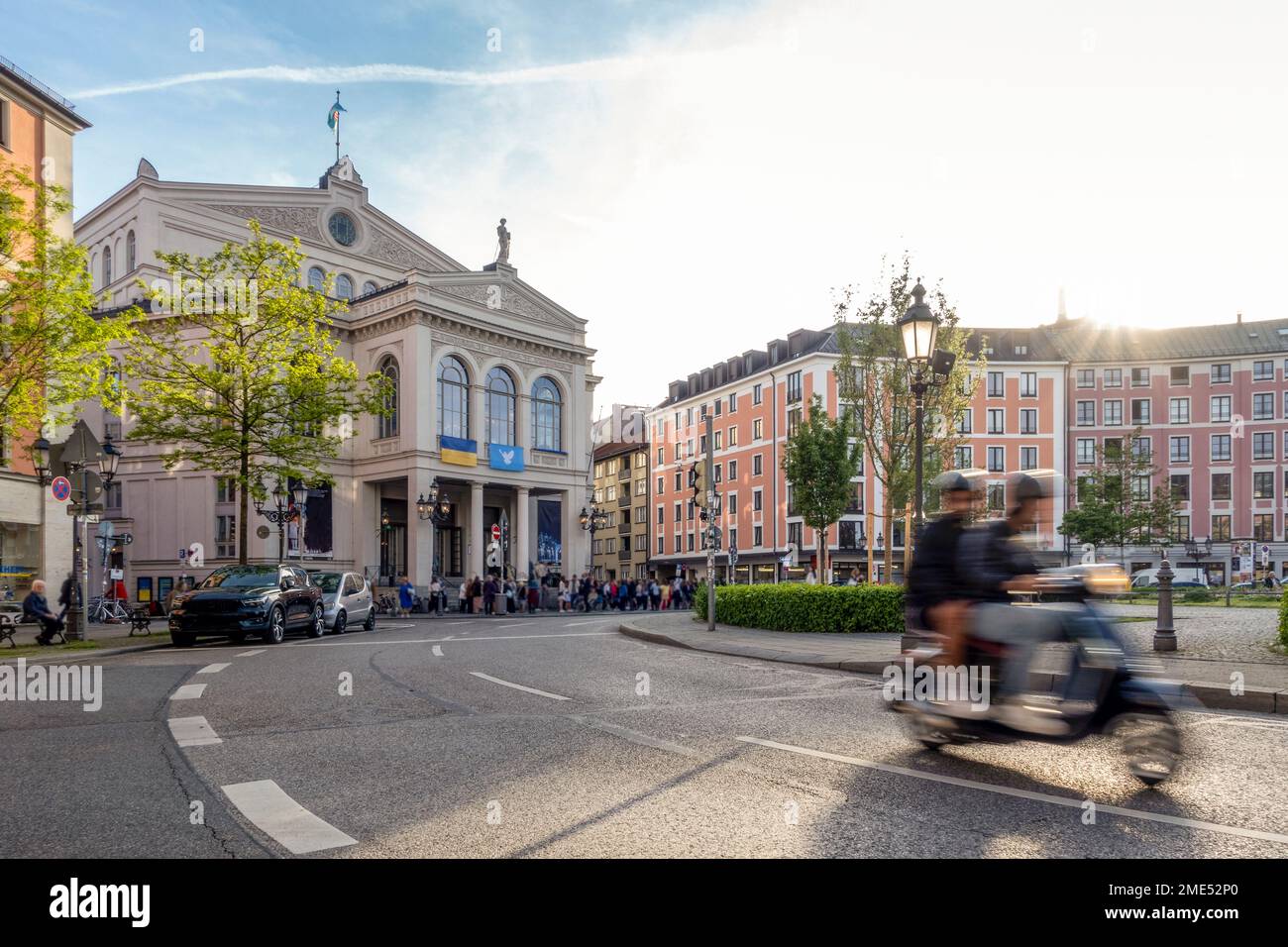 Germania, Baviera, Monaco di Baviera, movimento sfocato dello scooter a motore che passa attraverso piazza Gartnerplatz al tramonto Foto Stock