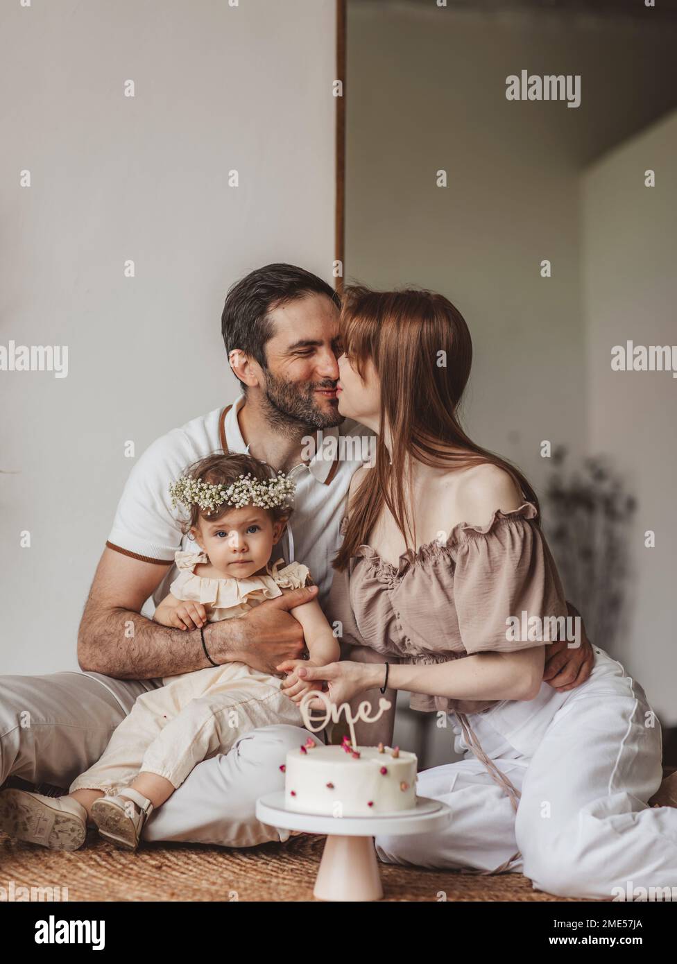 Genitori e figlia seduti con torta di compleanno a casa Foto Stock