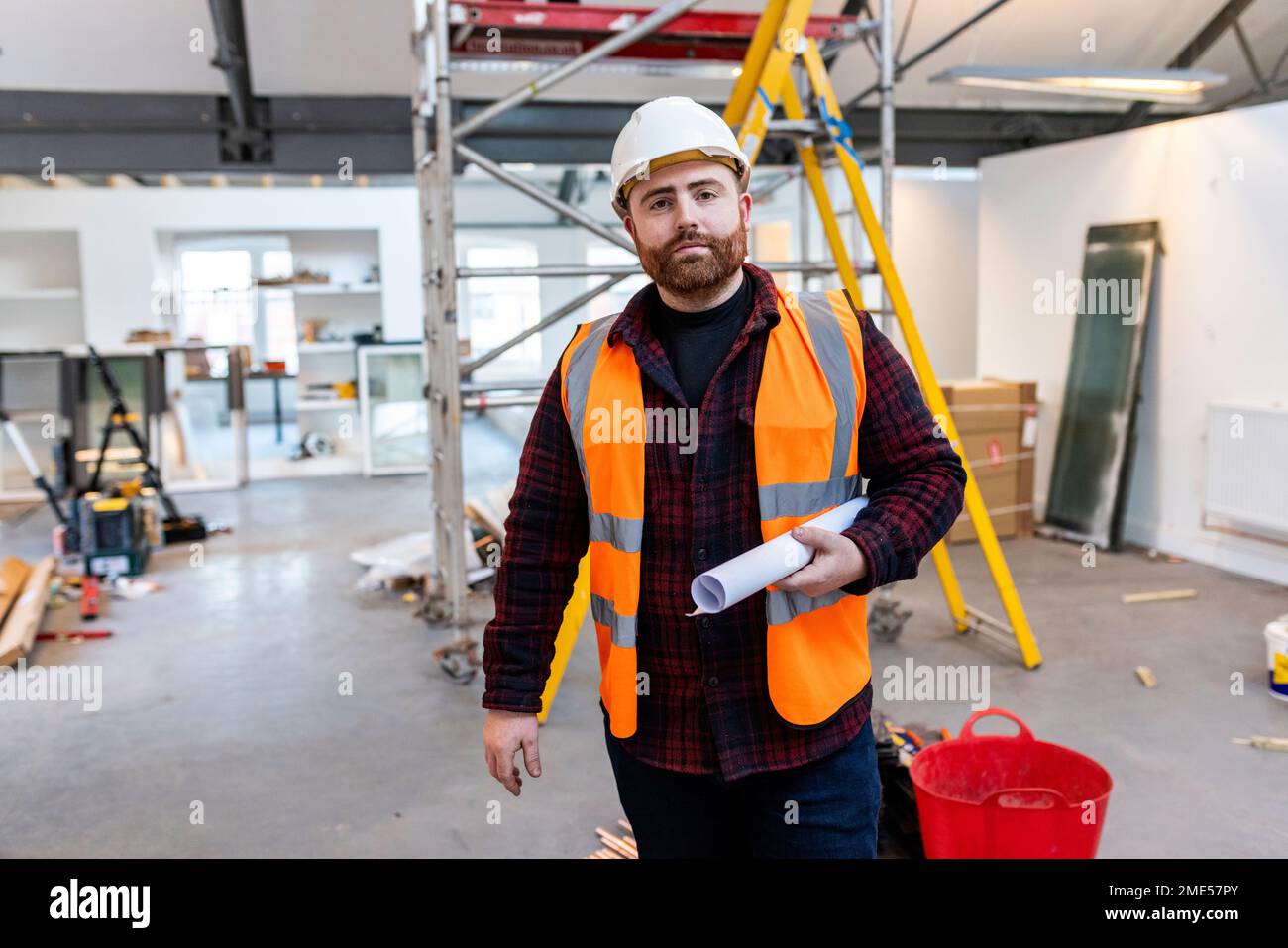 Ingegnere in piedi con documento in cantiere Foto Stock
