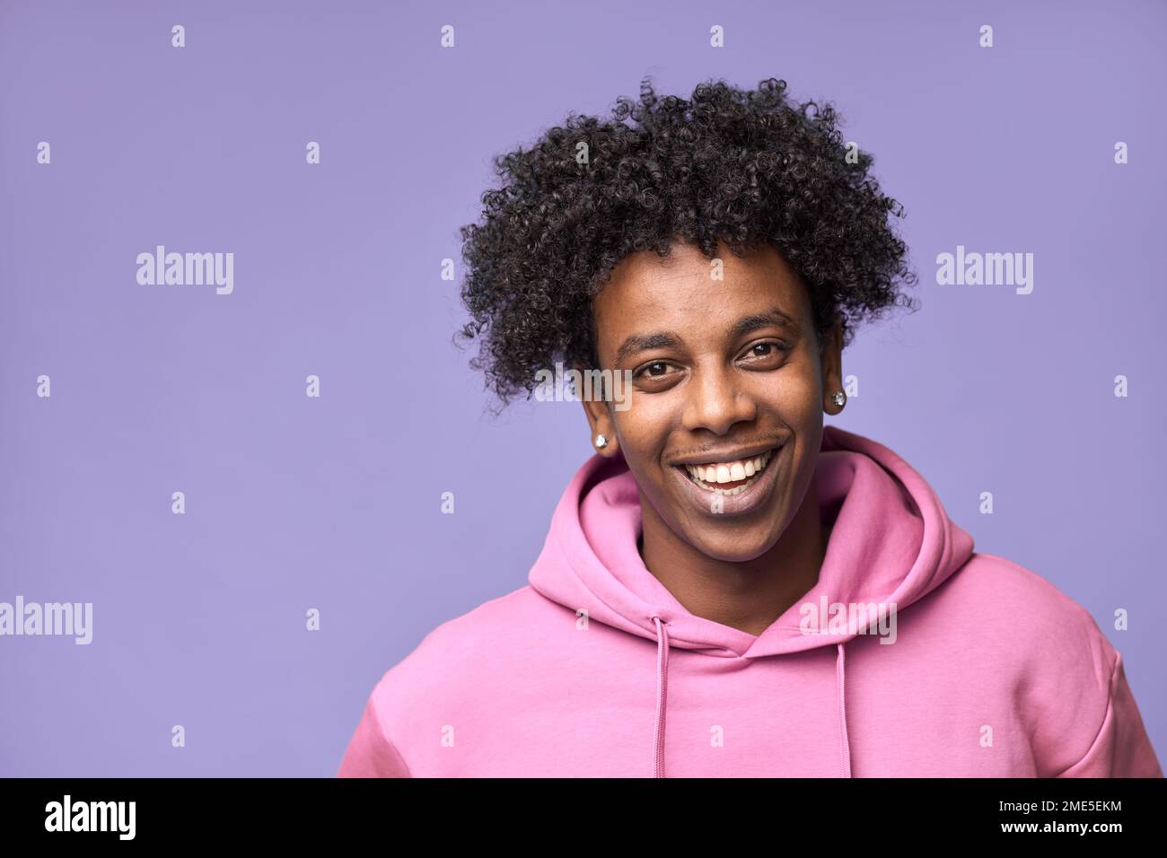 Ragazzo afro-americano sorridente che indossa felpa con cappuccio rosa isolato sul viola. Foto Stock
