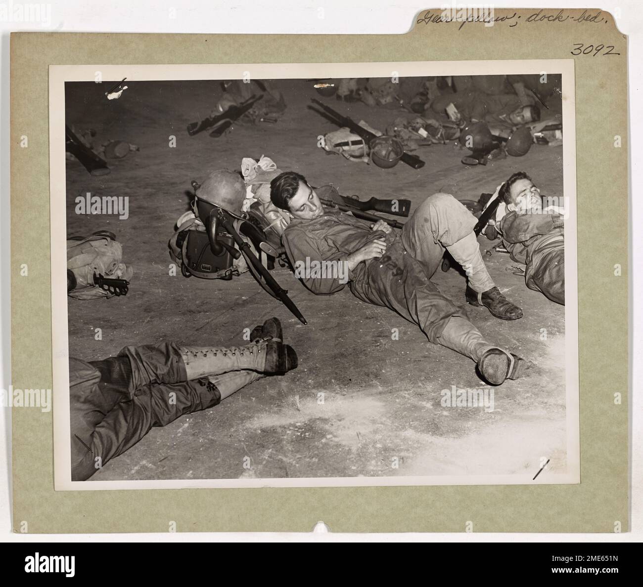 Un soldato si riposa brevemente alla vigilia di un'invasione nel Pacifico meridionale, usando la sua attrezzatura come cuscino a bordo di una nave da trasporto con equipaggio della Guardia Costiera. Questo momento di tregua mette in evidenza la stanchezza e la prontezza dei soldati prima di una missione di combattimento. Foto Stock