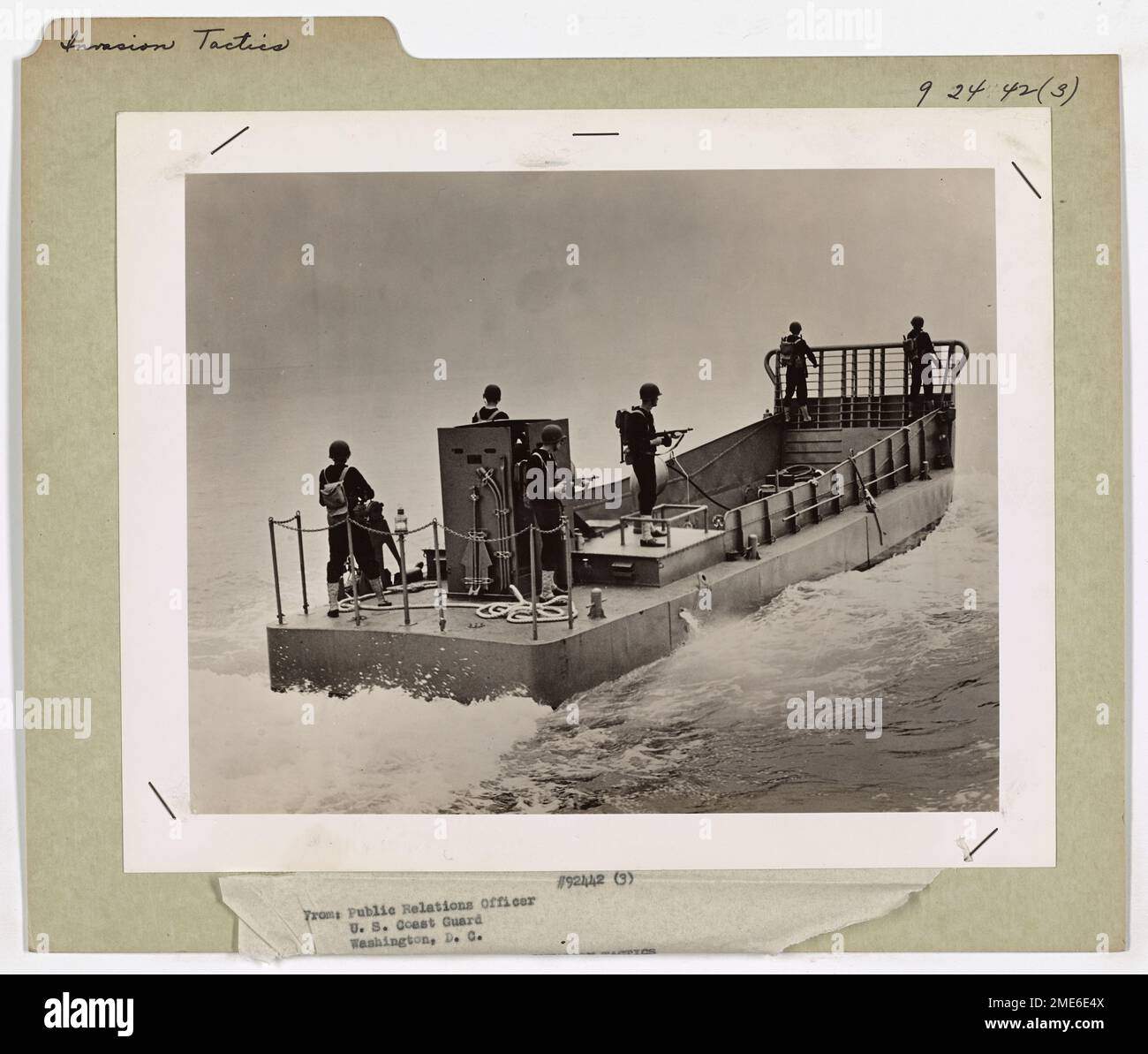 Le guardie costiere con elmetto d'acciaio sono pronte a bordo di una chiatta d'invasione, preparate a respingere le forze nemiche durante l'esecuzione delle tattiche d'invasione. L'immagine mette in evidenza la disponibilità e la vigilanza richieste al personale della Guardia Costiera durante gli assalti anfibi. Foto Stock