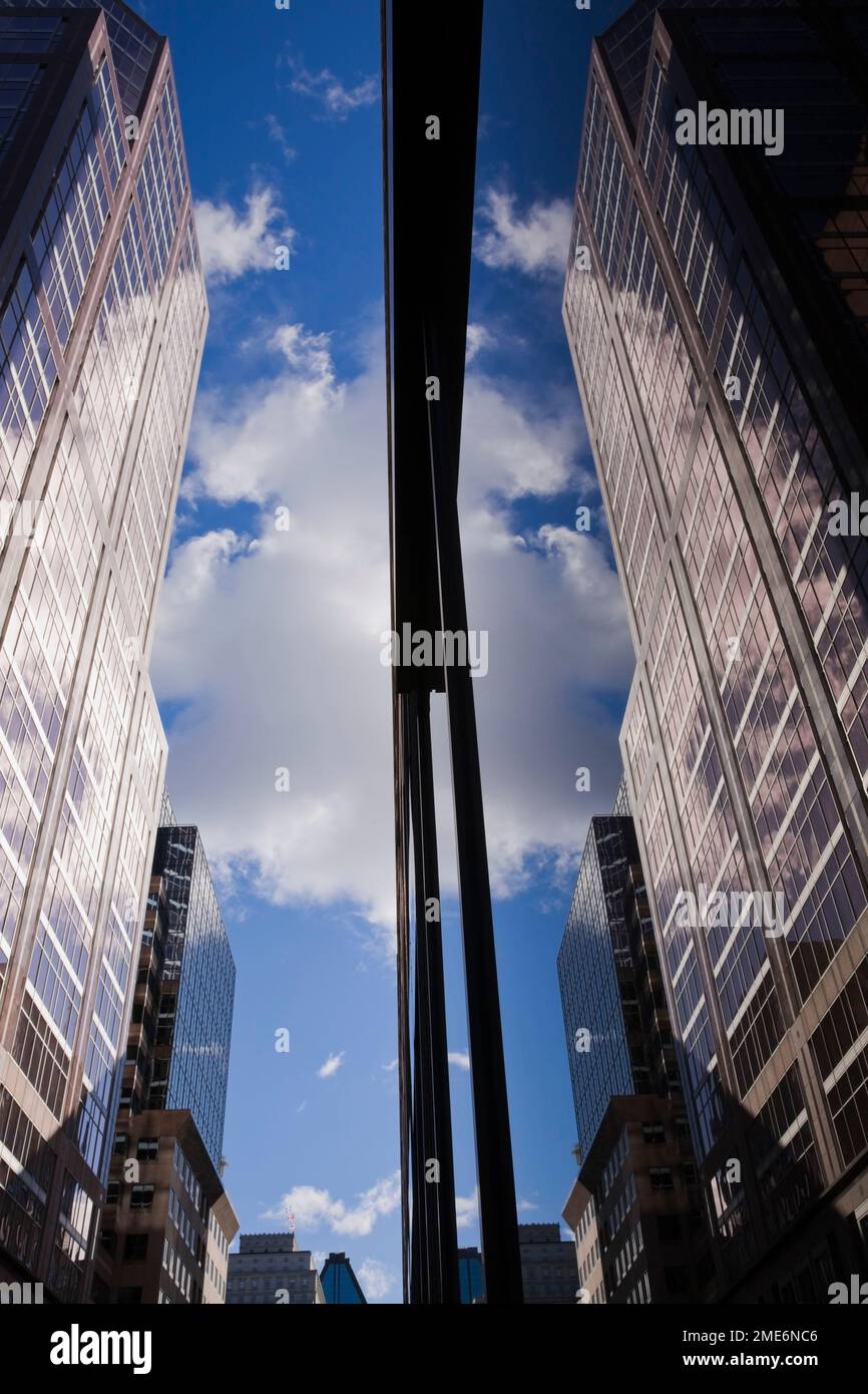Immagine speculare di edifici con cielo blu e nuvole riflesse nella grande finestra di vetro, Montreal, Quebec, Canada. Foto Stock