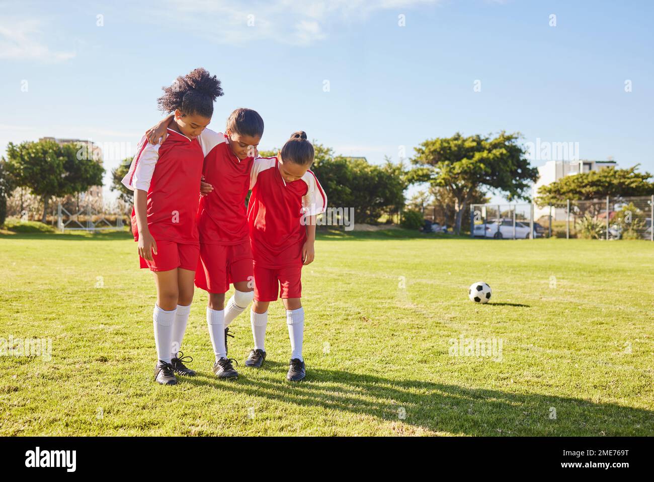 I bambini, il calcio e la squadra delle ragazze aiutano, sostengono e camminano con l'amico infortunato al campo di calcio. Lesioni sportive, bambini e gruppo di giocatori di calcio aiutare Foto Stock