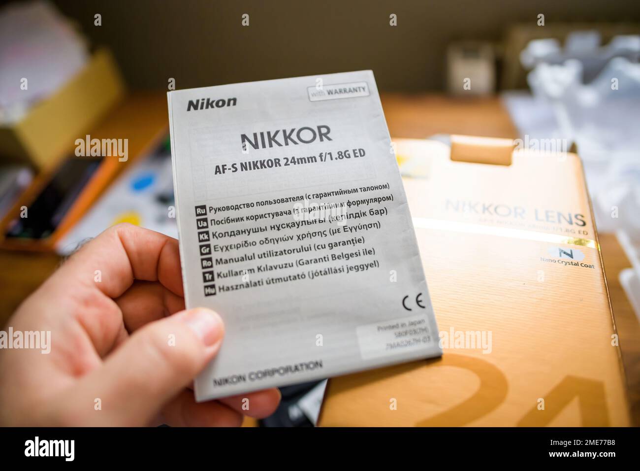 Parigi, Francia - 16 gennaio 2023: Manuale di istruzioni per la tenuta della mano maschile prospettiva POV per la nuova lente Nikon AF-s Nikkor 25mm f 1,8 G ed in russo, ucraino, greco, rumeno turco e ungherese Foto Stock