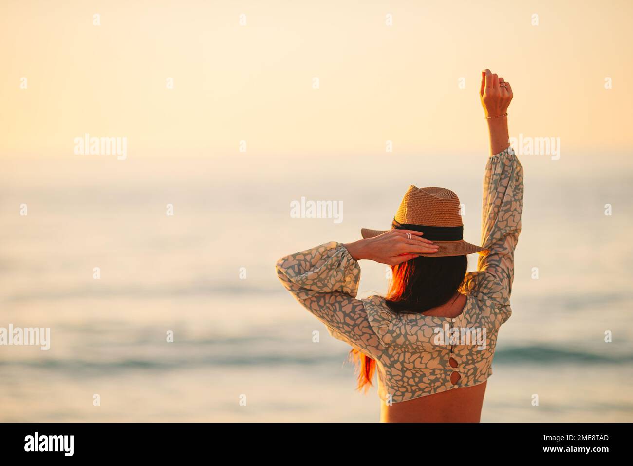 Giovane donna bella al cappello di paglia sulla spiaggia al tramonto Foto Stock