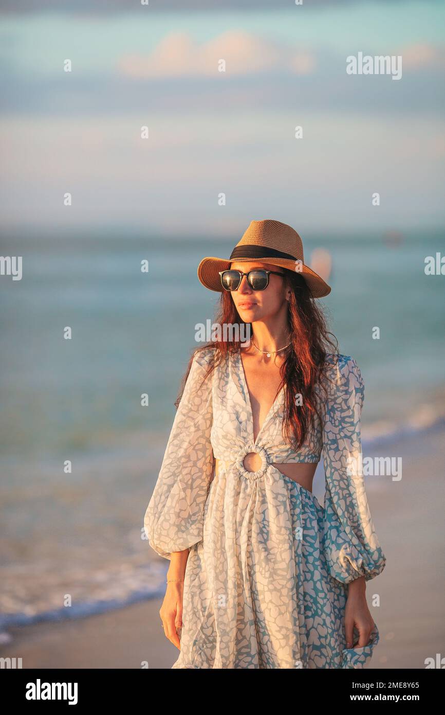 Giovane donna bella al cappello di paglia sulla spiaggia al tramonto Foto Stock