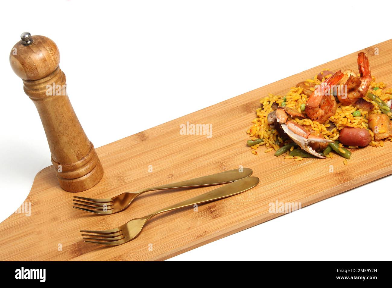 Riso paella servito su un asse di legno con shaker di sale e forchette preparate con frutti di mare, amaroni, zafferano, salsiccia, carne. Piatto tradizionale di Valenci Foto Stock