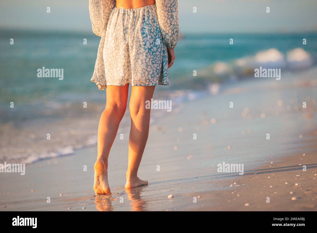 Gambe femminili sul primo piano della spiaggia. Donna in abito a piedi sulla spiaggia Foto Stock