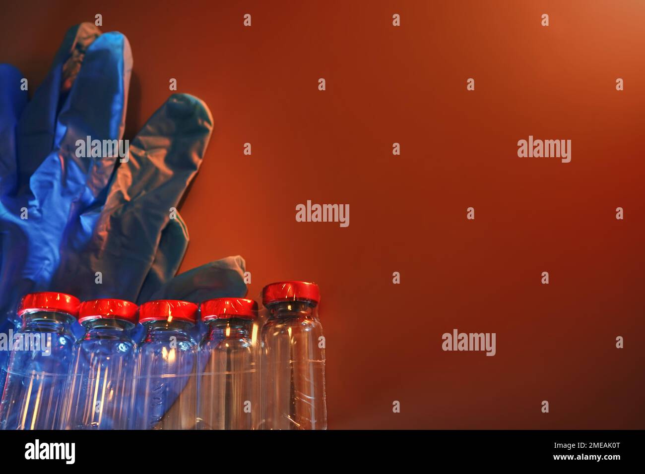 Guanti e fiale per uso medico su sfondo marrone per contenitori per iniezione ad ago Foto Stock