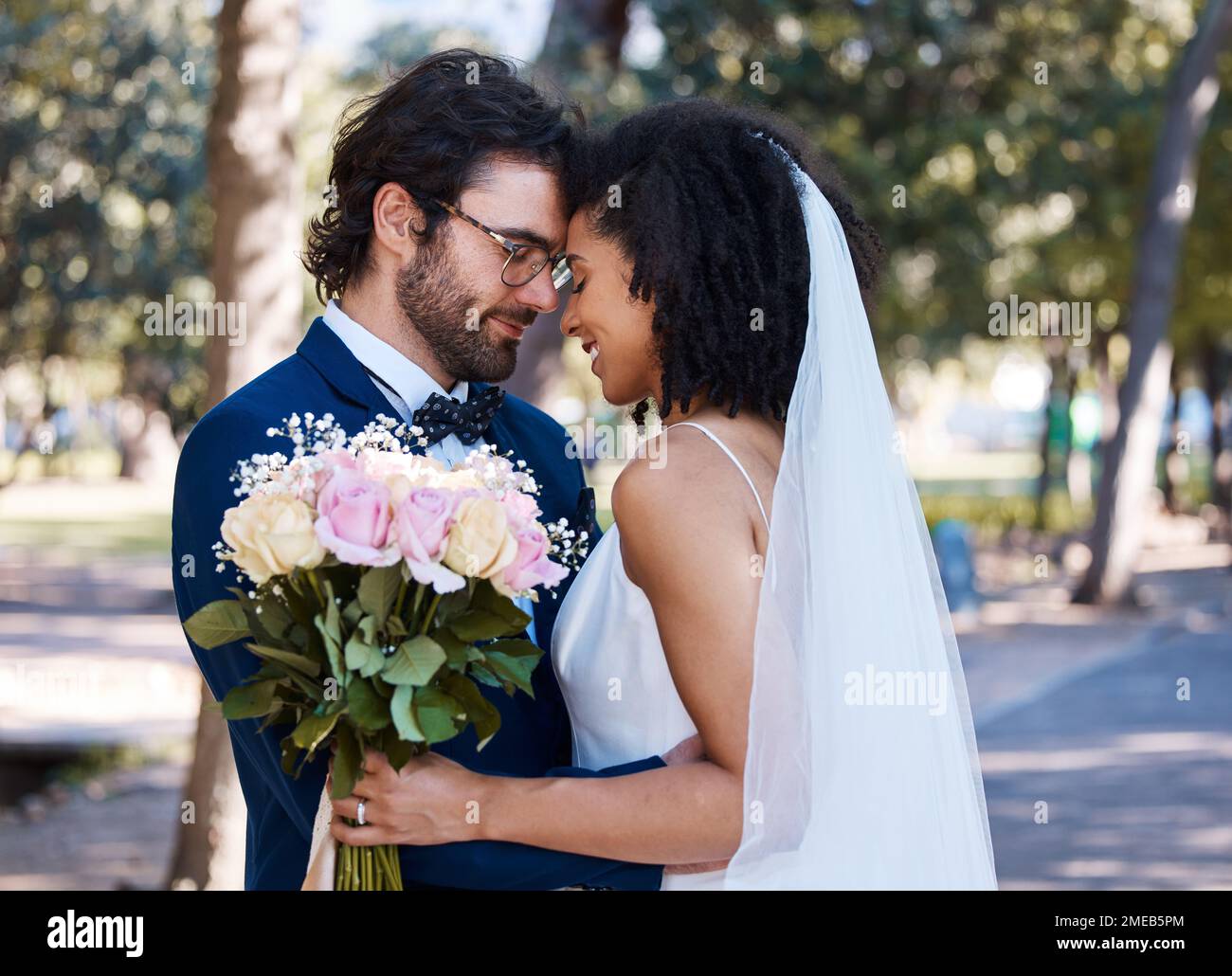 Coppia sposata, fiore bokeh e sorriso per matrimonio, matrimonio o amore impegno insieme nel parco. Sposo felice e sposa sorridente nella felicità per Foto Stock