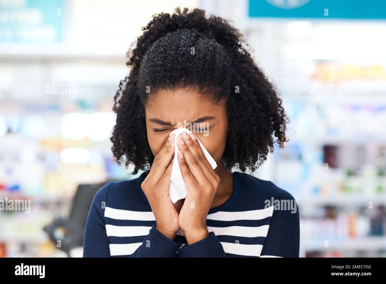 Youll trovare il trattamento di cui avete bisogno in farmacia. una giovane donna che soffia il naso in farmacia. Foto Stock
