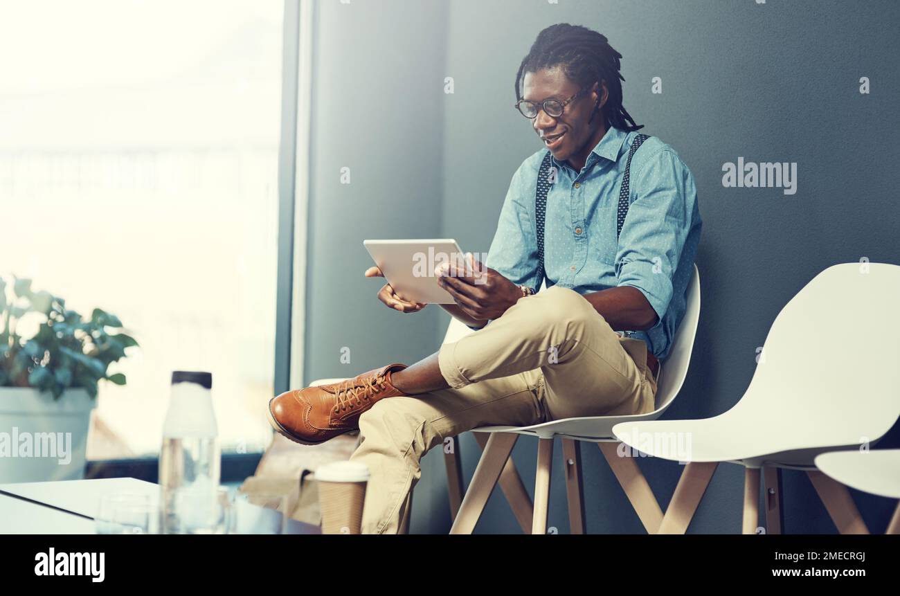 Tutto quello che ho bisogno di sapere su questo lavoro con un semplice tocco. un giovane uomo d'affari che usa un tablet in attesa di un colloquio. Foto Stock