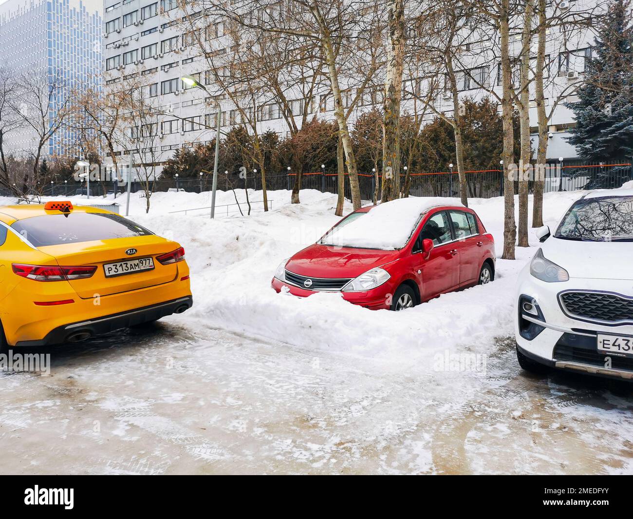 Mosca. Russia. Gennaio 23, 2023. Un'auto rossa Nissan Tiida è congelata in un mucchio di neve in un parcheggio cittadino. Foto Stock