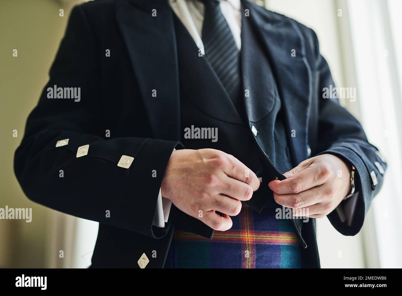 Ultimi tocchi finali. un uomo irriconoscibile che indossa una giacca per prepararsi a un matrimonio all'interno di un edificio durante il giorno. Foto Stock