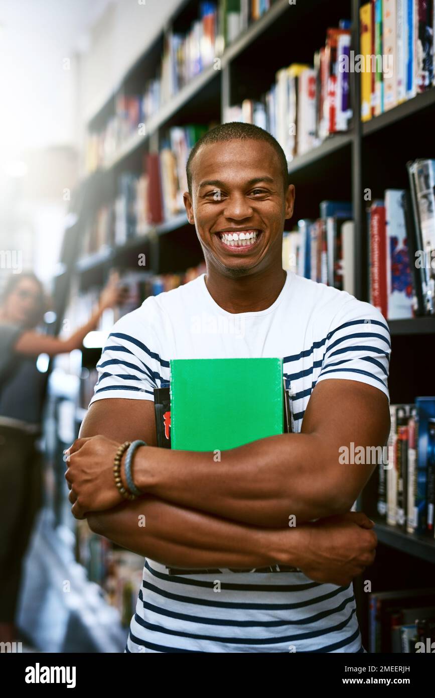 Questa è la mia storia di successo accademico. Ritratto di un giovane felice che trasporta i libri in una biblioteca all'università. Foto Stock