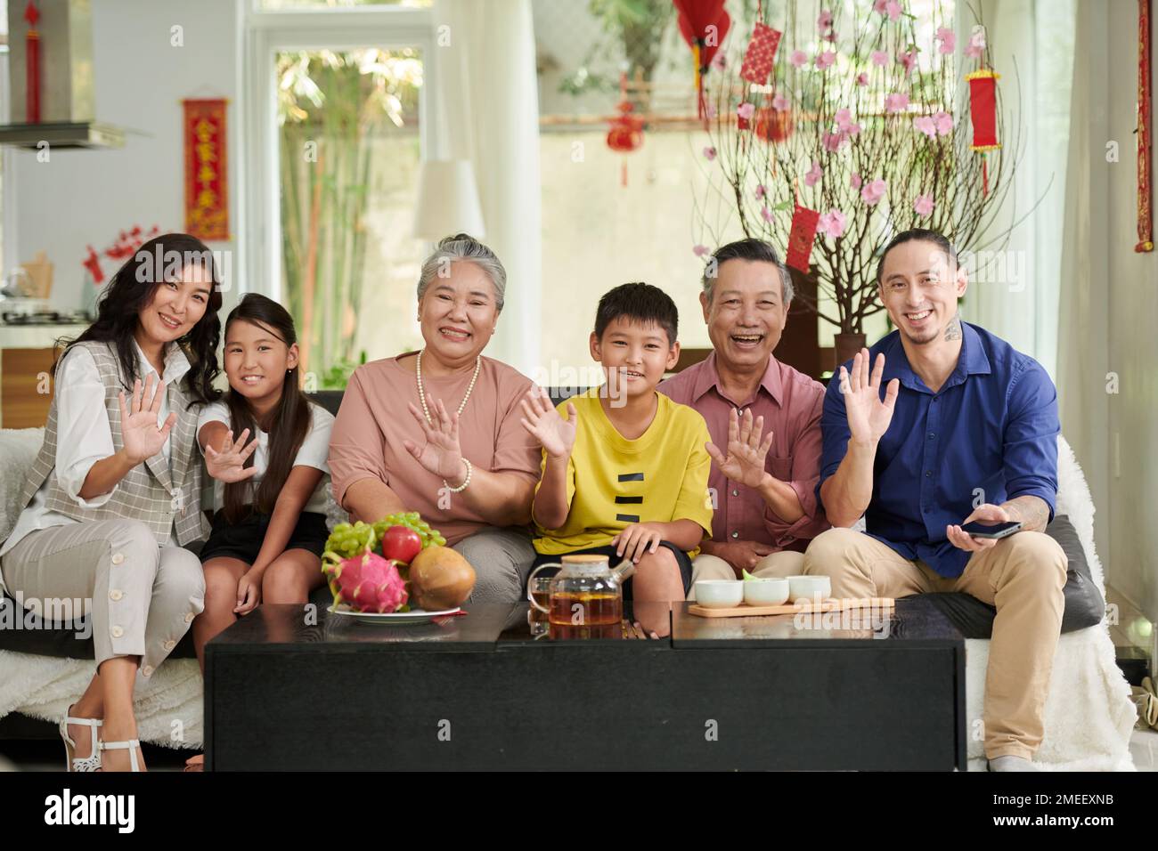 Felice grande famiglia che ha il tè e frutta fresca a casa quando festeggia il Tet Foto Stock